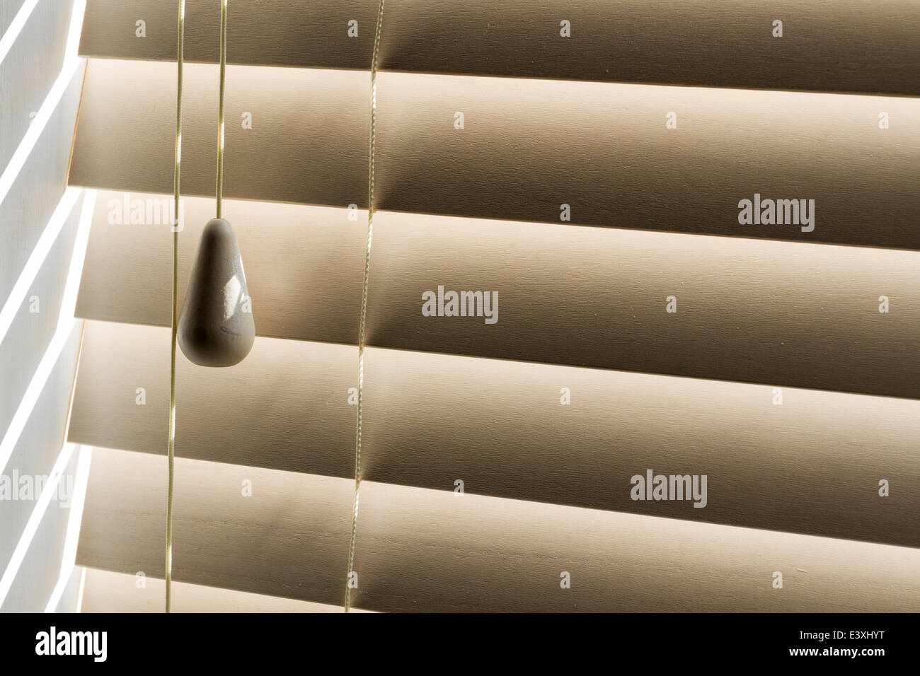 Sunlight streaming through blind slats with pull cord Stock