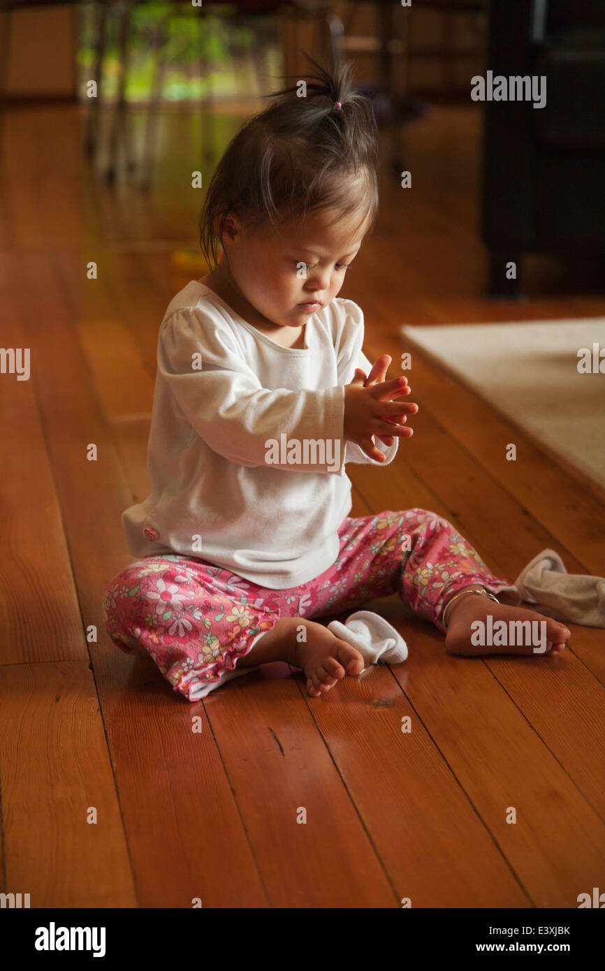 Mixed race baby with Down syndrome playing on floor Stock Photo Alamy