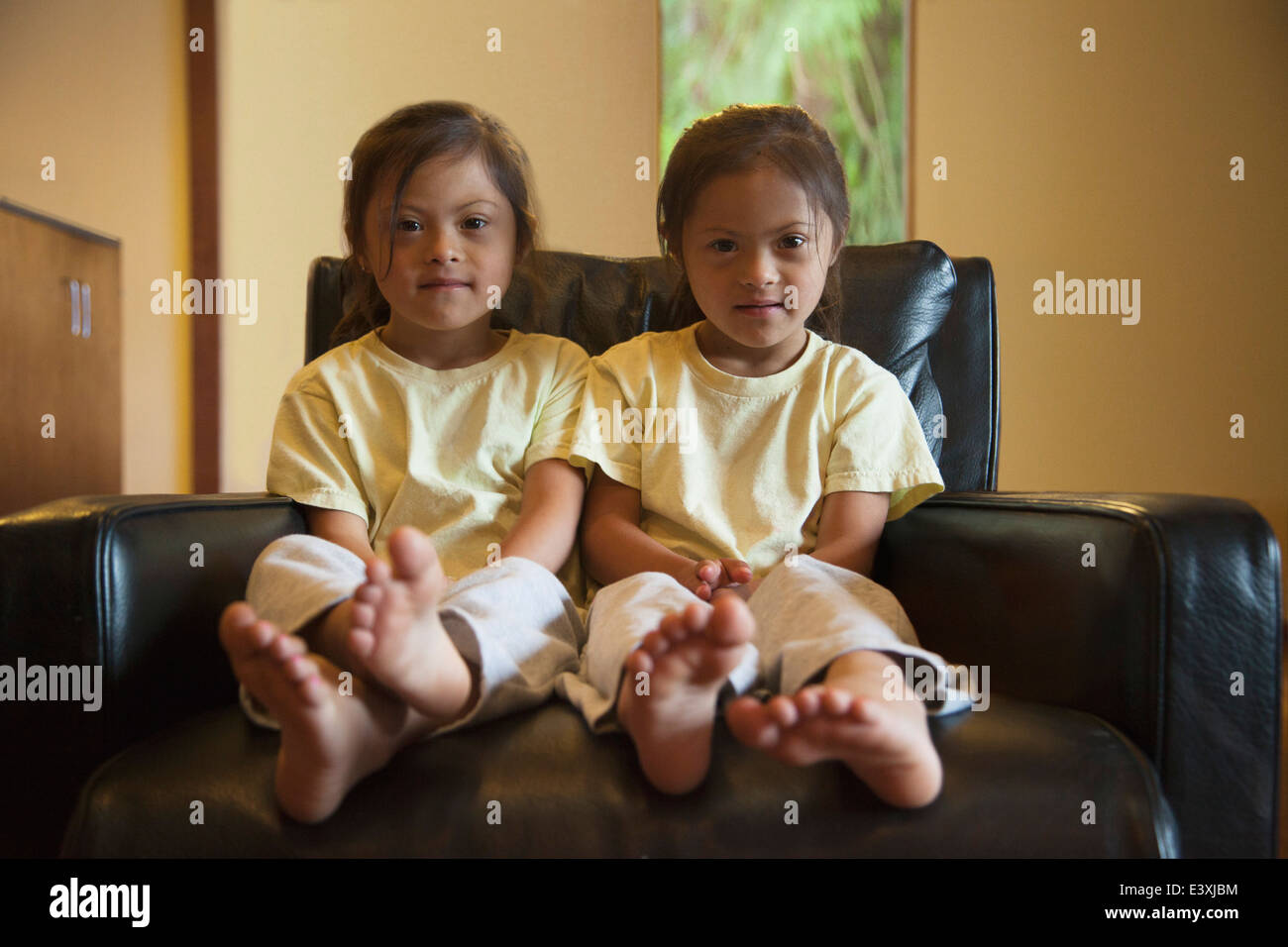 Mixed race twins with Down syndrome sitting in armchair Stock Photo Alamy