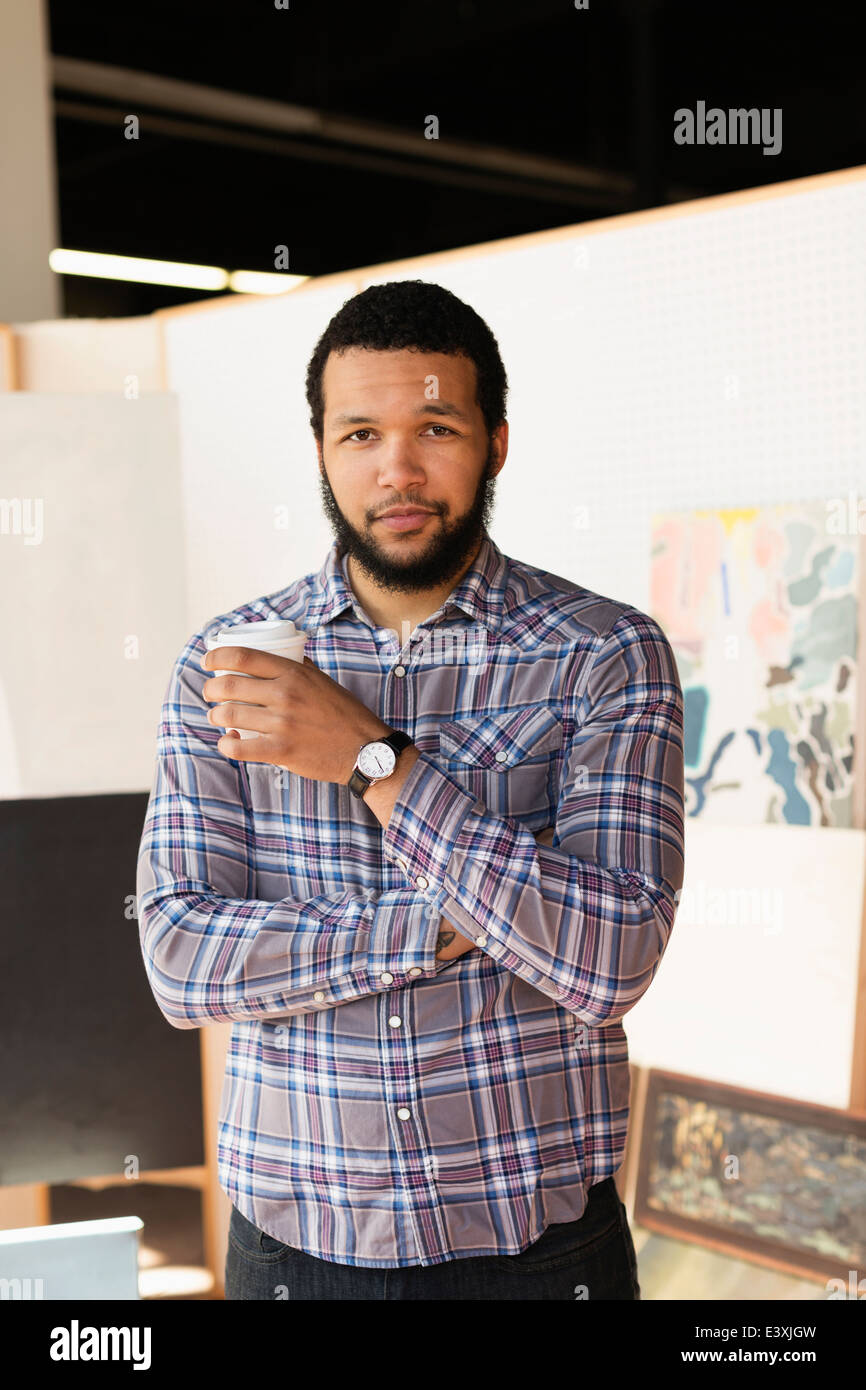 Mixed race artist drinking coffee in studio Stock Photo Alamy