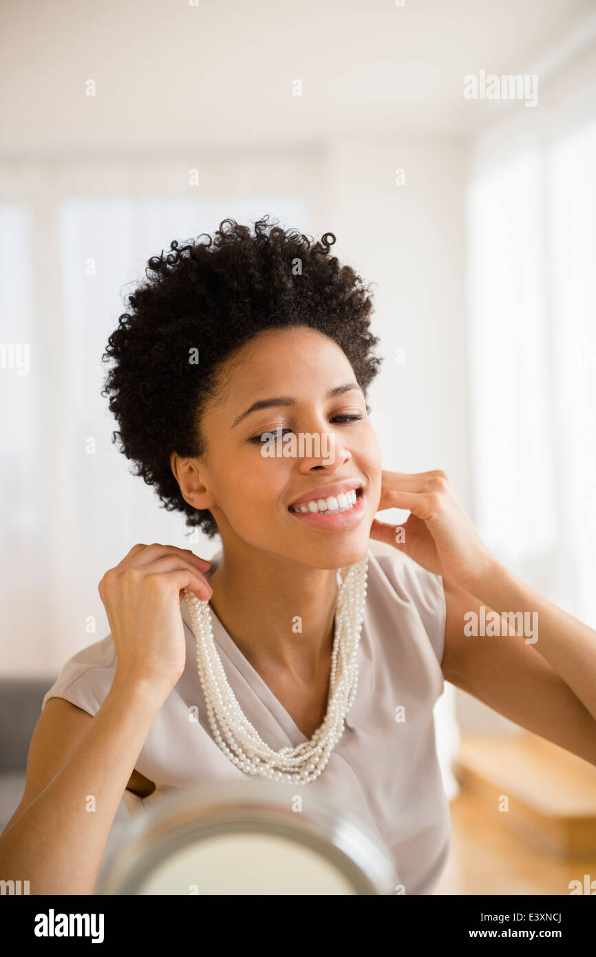 Black woman trying on necklace in mirror Stock Photo