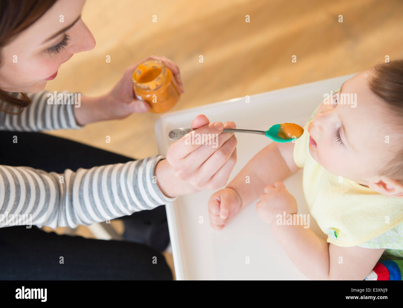 Mother feeding baby in high chair Stock Photo