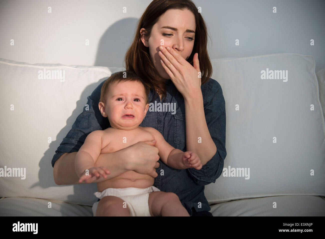 Tired mother holding crying baby Stock Photo