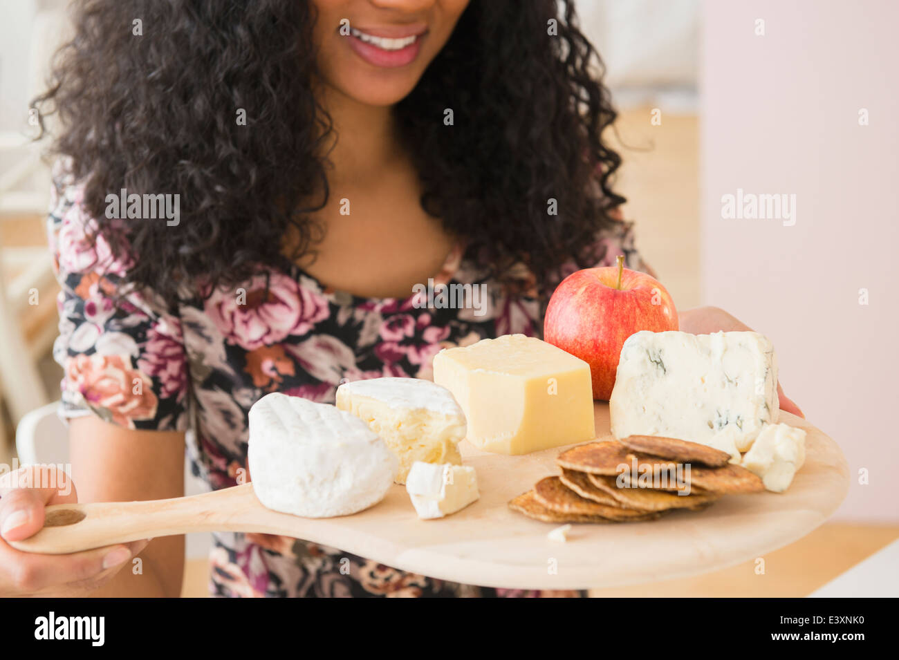 Mixed race woman carrying fruit and cheese board Stock Photo
