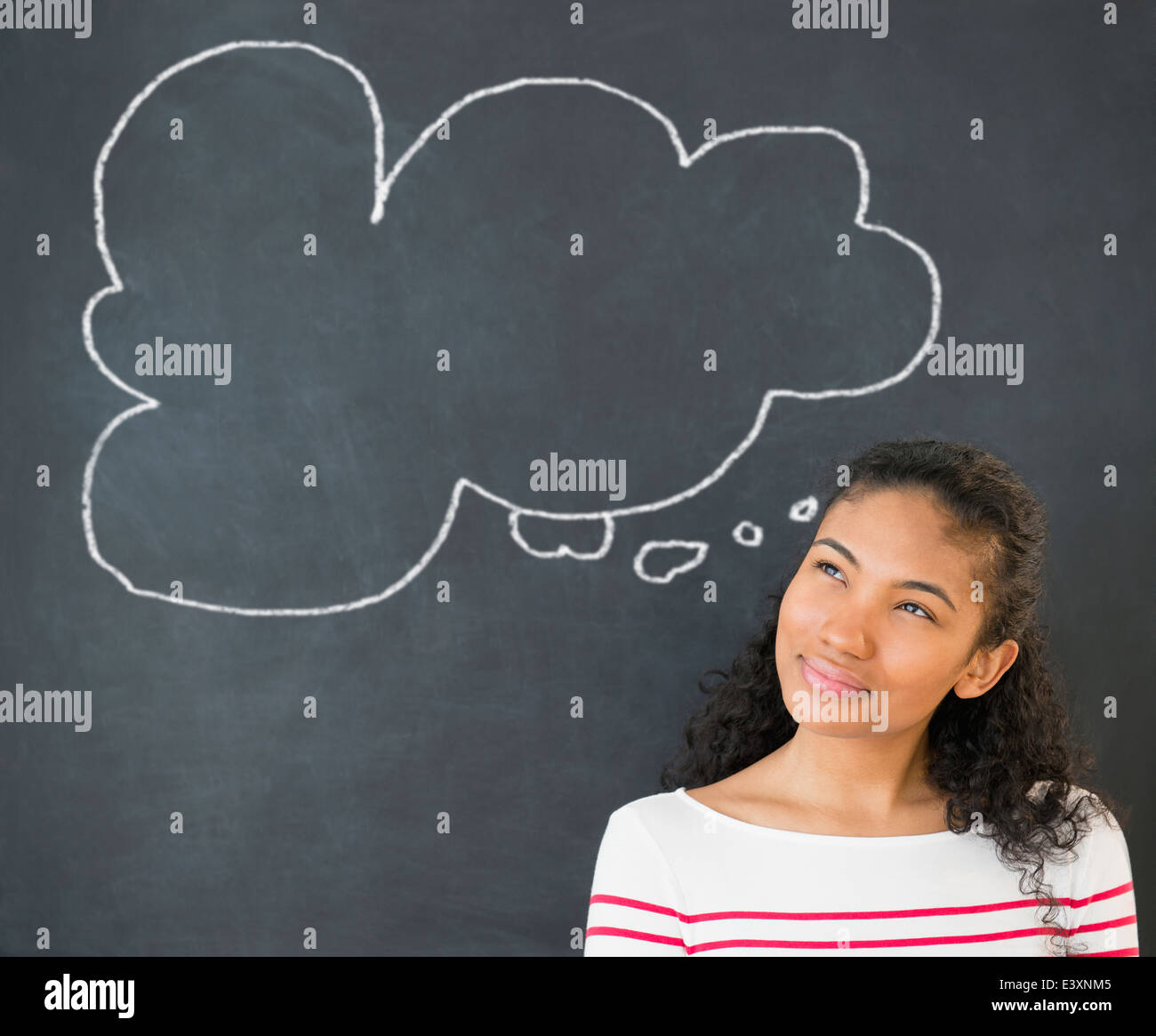 Mixed race woman under thought bubble on chalkboard Stock Photo