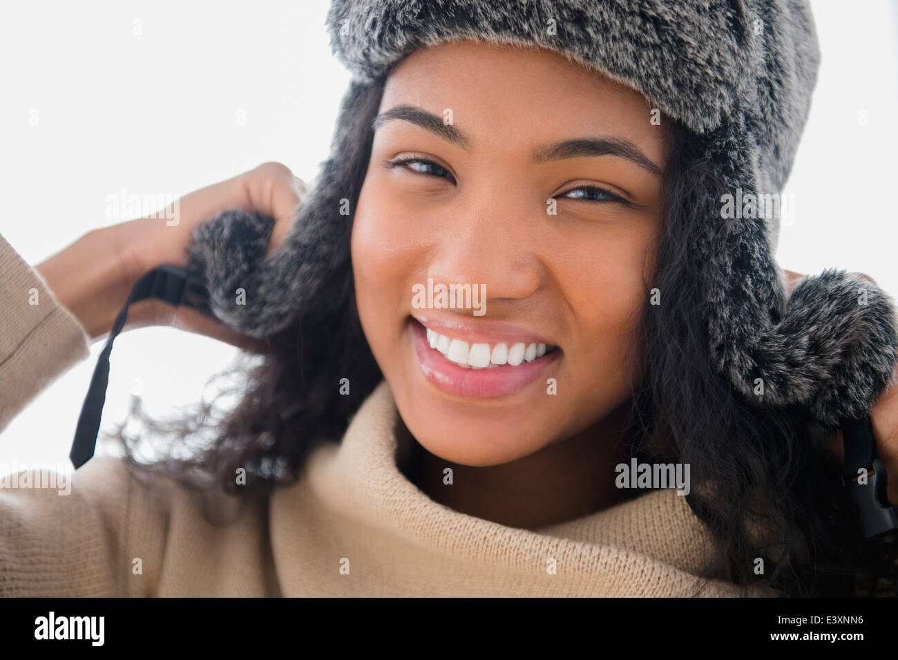 Mixed race woman wearing furry hat in snow Stock Photo