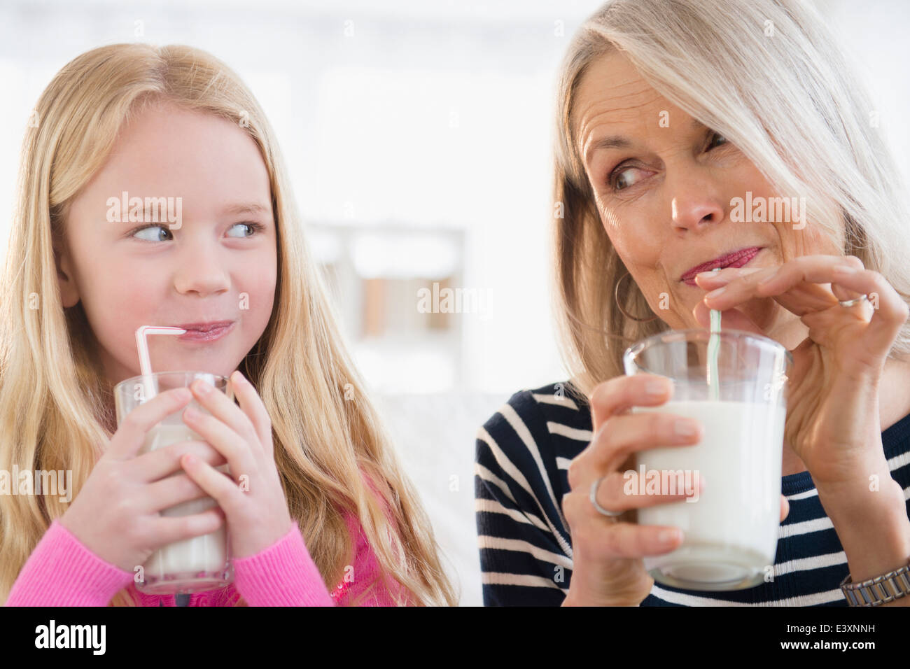 Senior Caucasian woman and granddaughter drinking milk Stock Photo