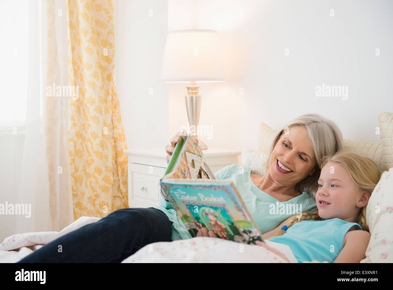 Senior Caucasian woman and granddaughter reading in bed Stock Photo