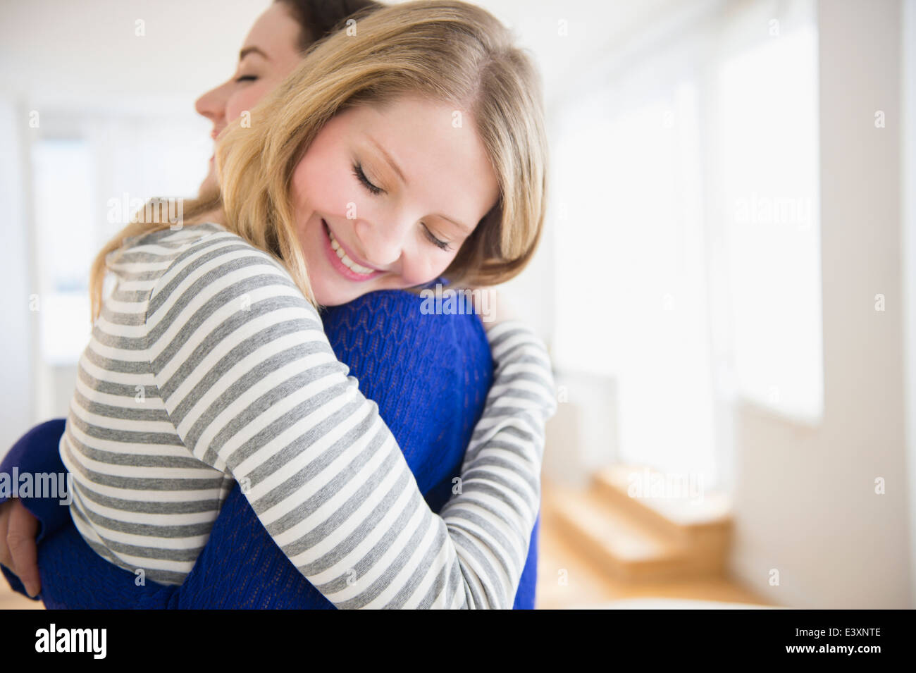 Women hugging in living room Stock Photo