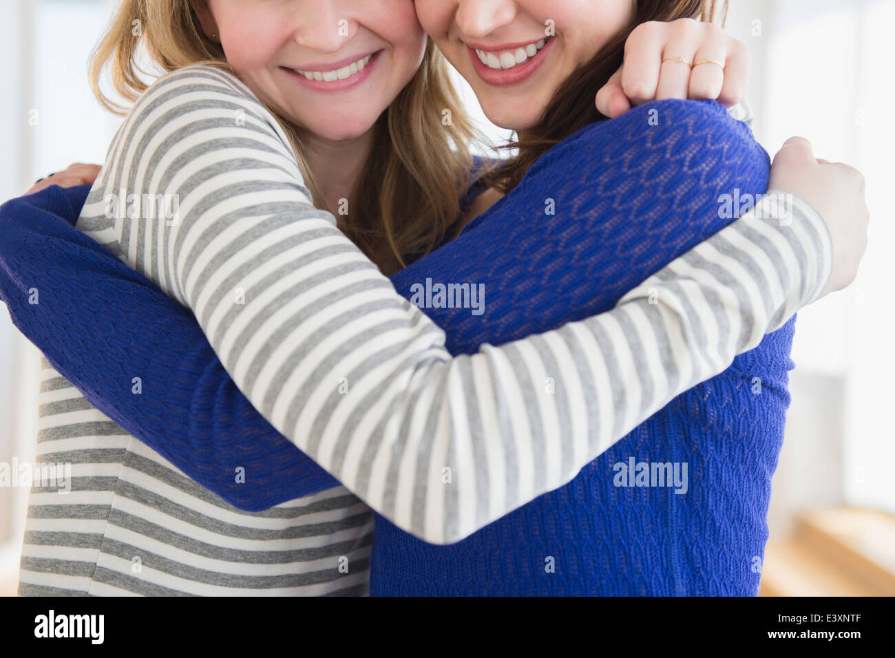 Women hugging in living room Stock Photo