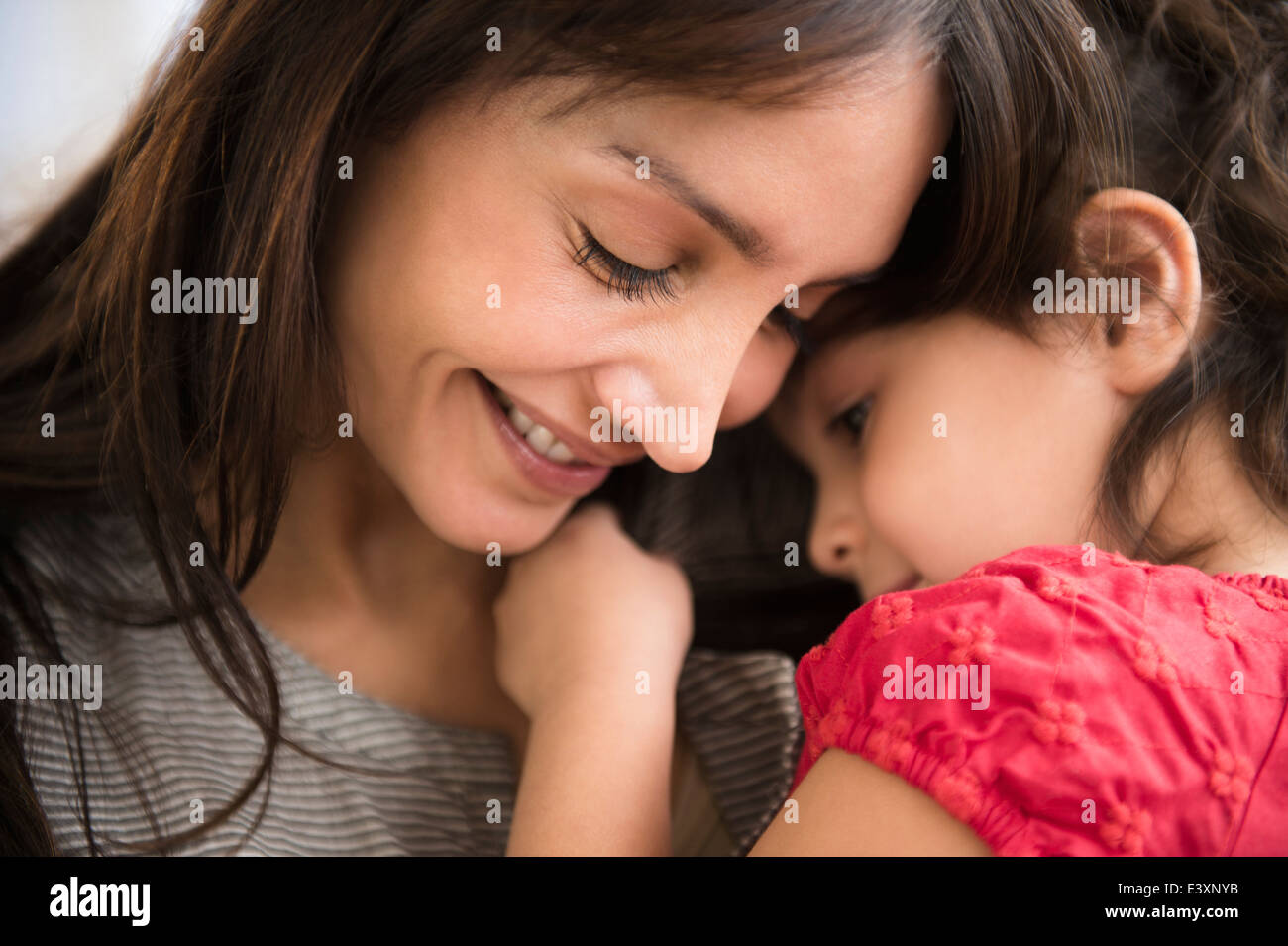 Hispanic girl whispering in mother's ear Stock Photo
