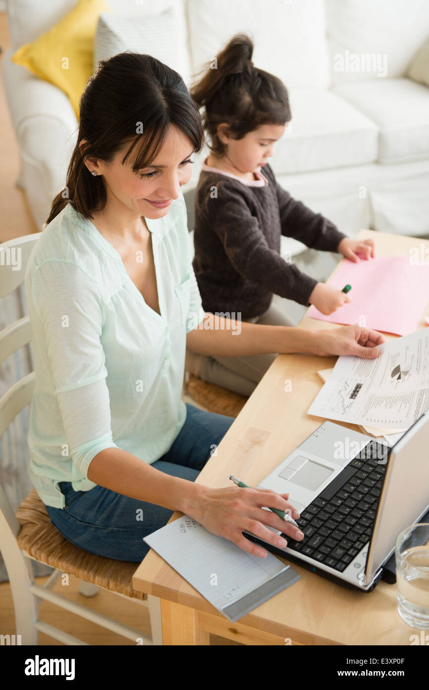 Hispanic mother and daughter working at table Stock Photo