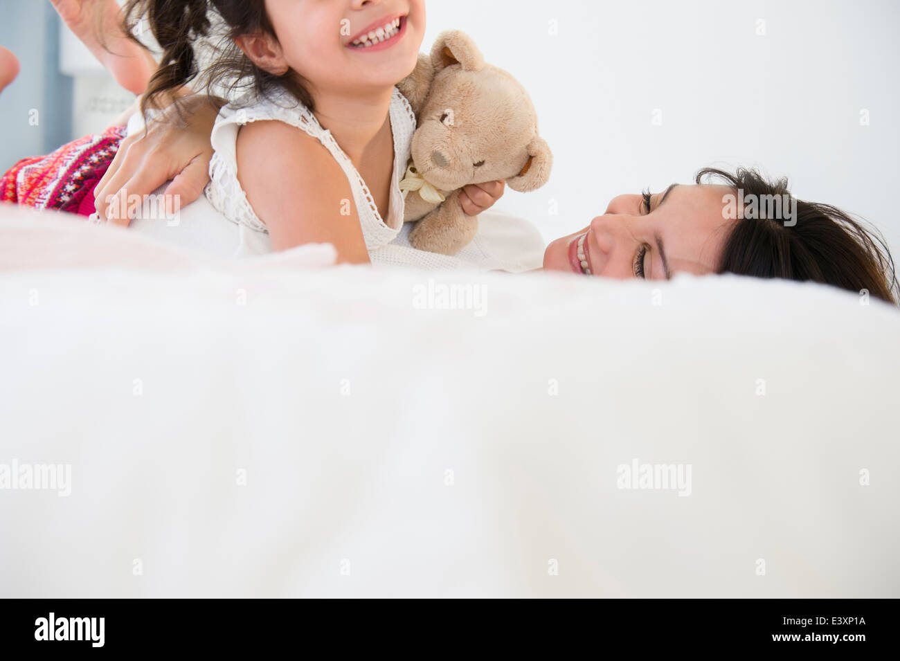 Hispanic mother and daughter relaxing on bed Stock Photo