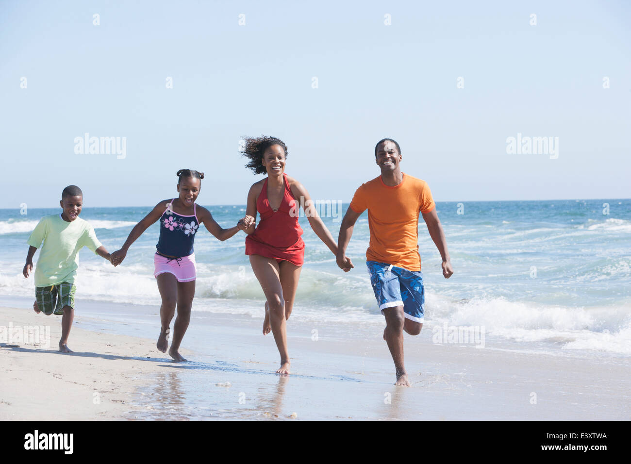 Family running in waves on beach Stock Photo - Alamy