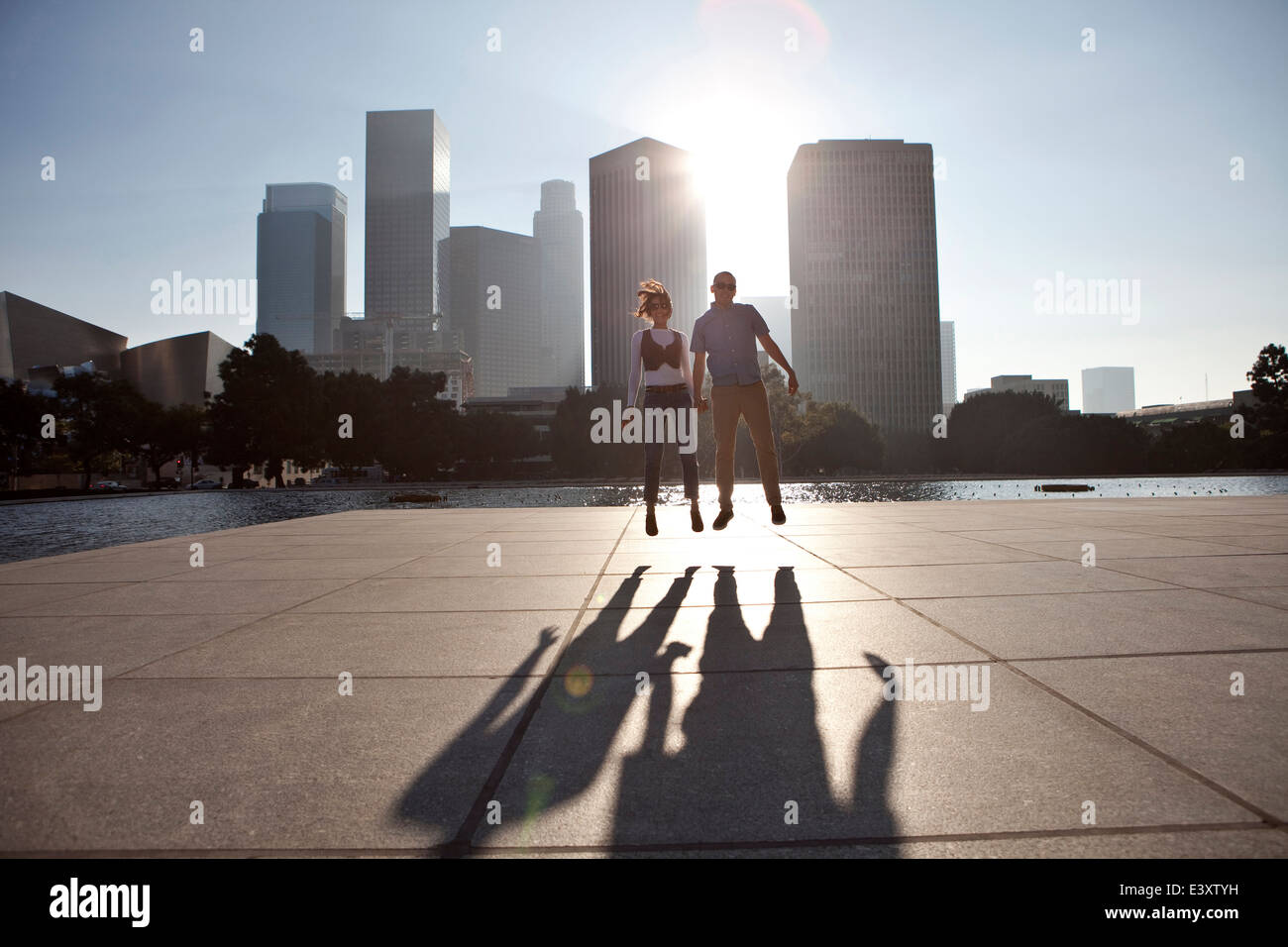 Couple casting shadows on urban waterfront Stock Photo