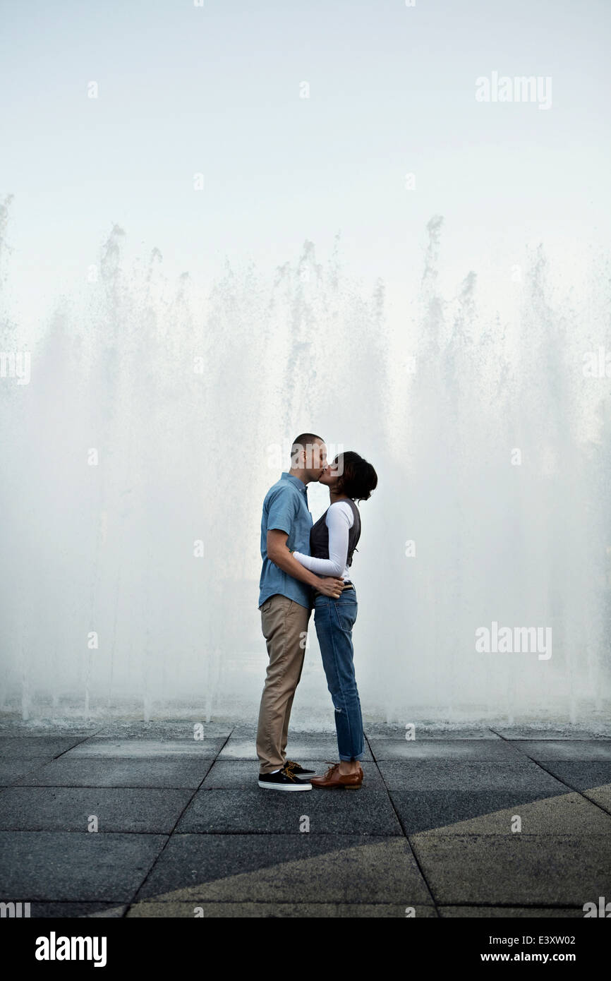 Couple kissing by urban fountain Stock Photo