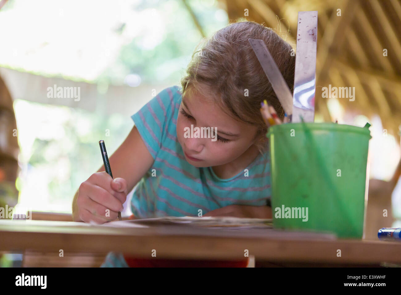 Caucasian girl writing at desk Stock Photo