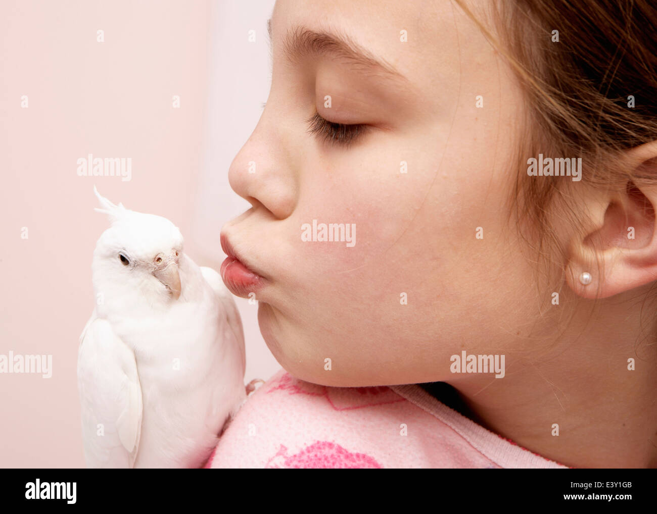 Mixed race girl kissing bird Stock Photo