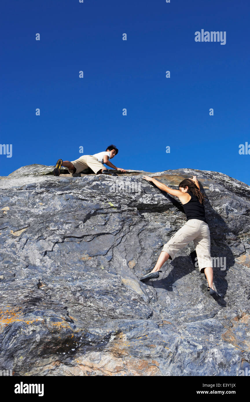 Climbers scaling steep rock face Stock