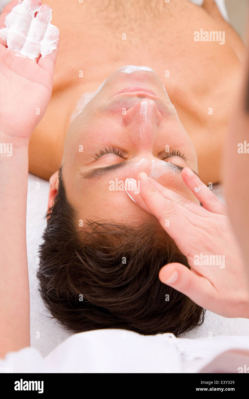 Beautician applying moisturizer man's face Stock Photo