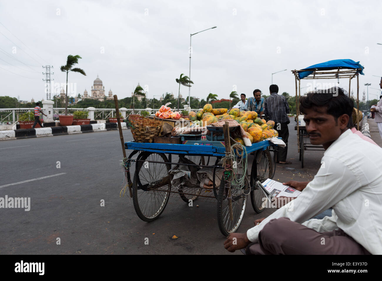 Papaya Vendor relaxing on a sidewalk in Hyderabad,India Stock Photo