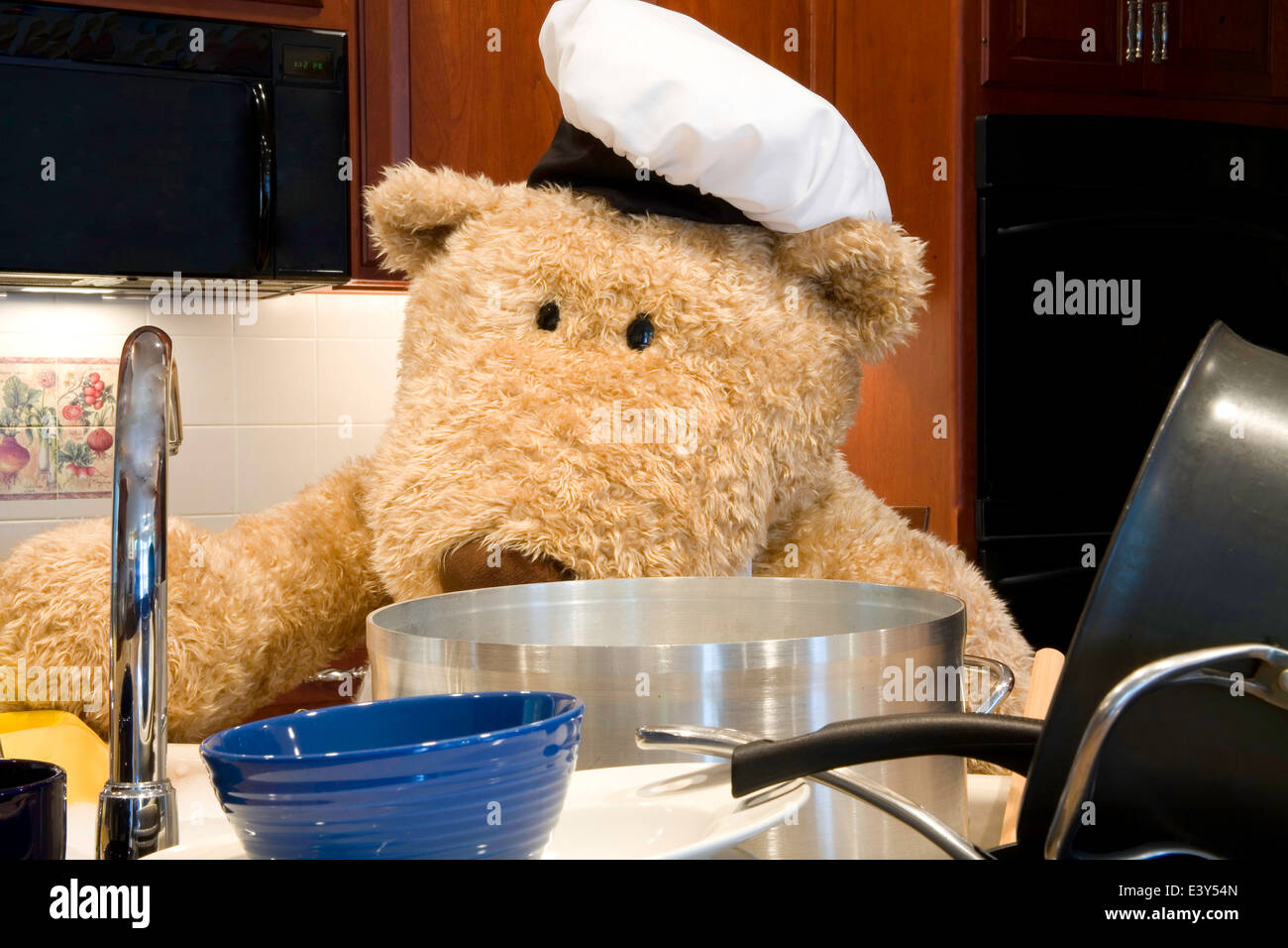 Oversized teddy bear dressed in chef's apron and hat in the kitchen