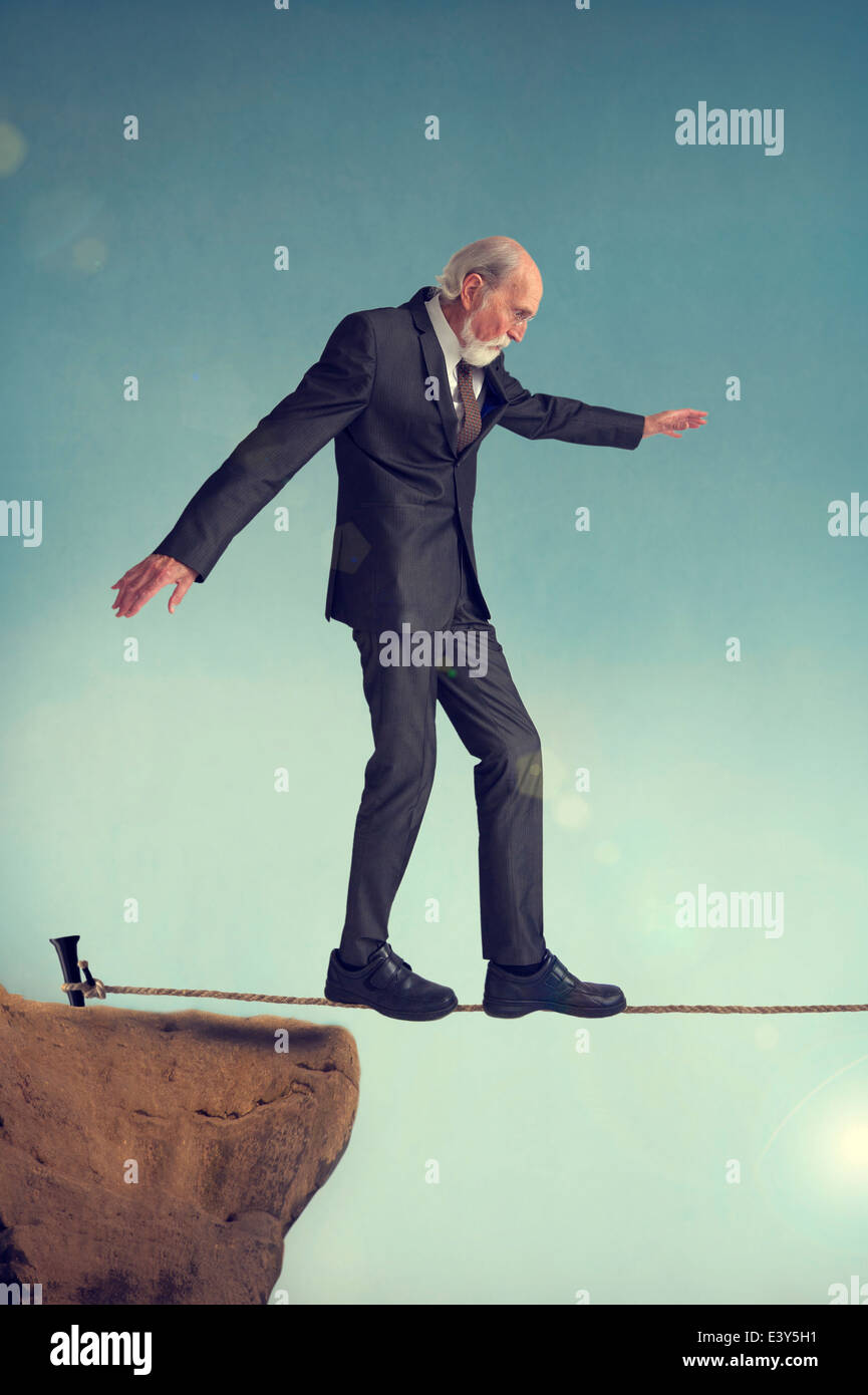 senior man walking on a tightrope or highwire Stock Photo