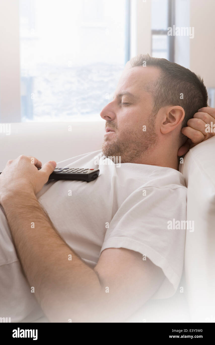 Mature man with remote control asleep on sofa Stock Photo