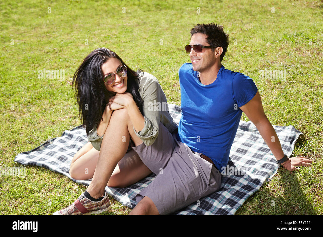 Couple sitting on picnic blanket in park Stock Photo