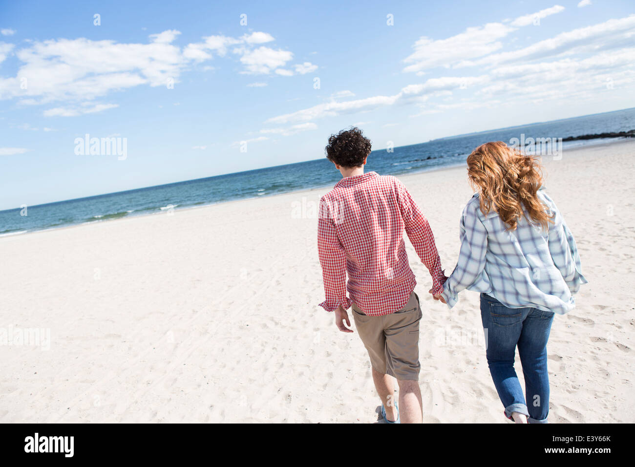 Romantic couple strolling hand in hand on beach Stock Photo - Alamy