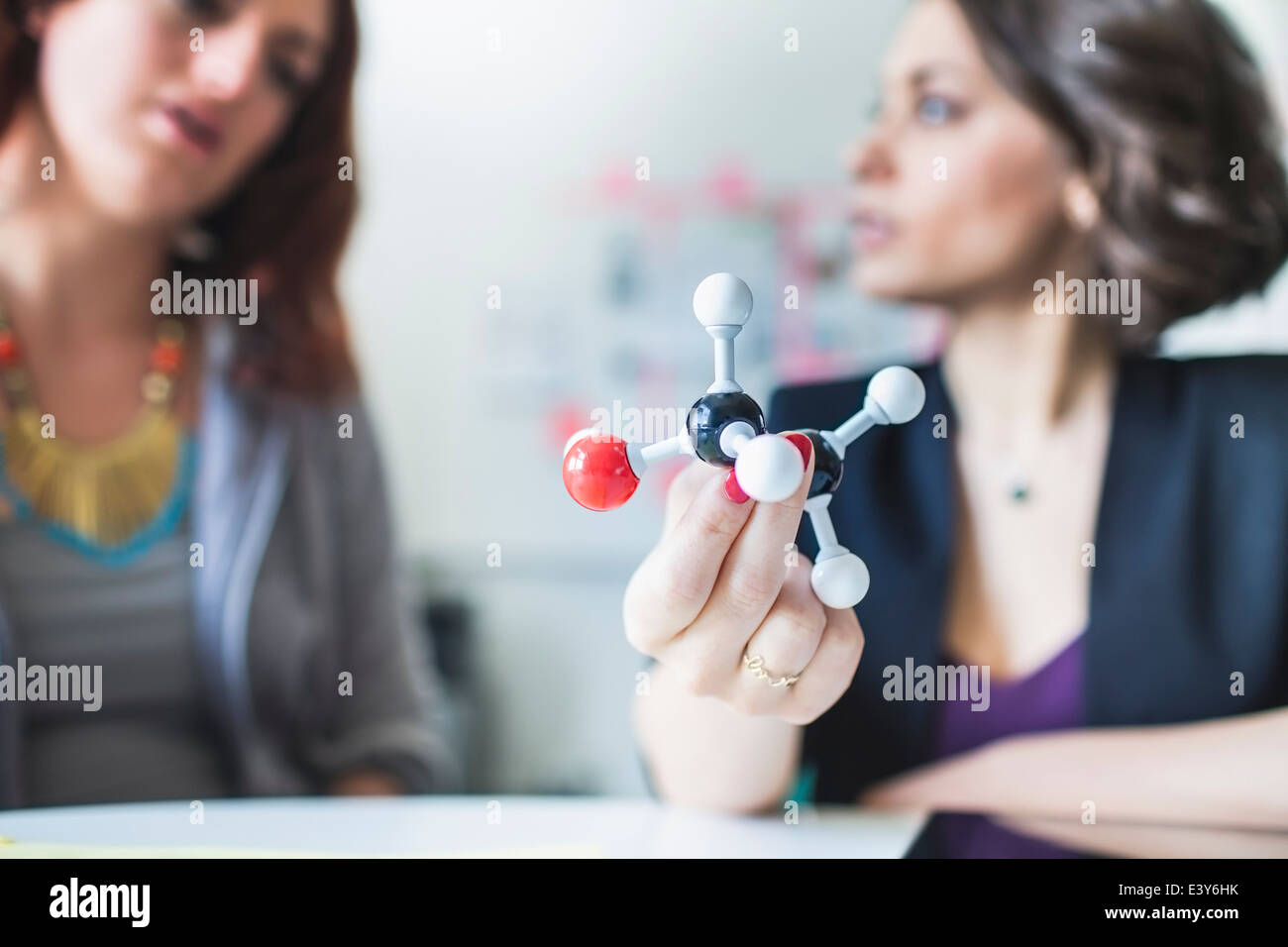 Young women discussing molecular model of Ethanol molecule Stock Photo