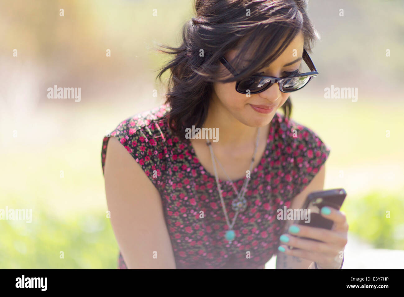 Young woman sitting in park with smartphone Stock Photo