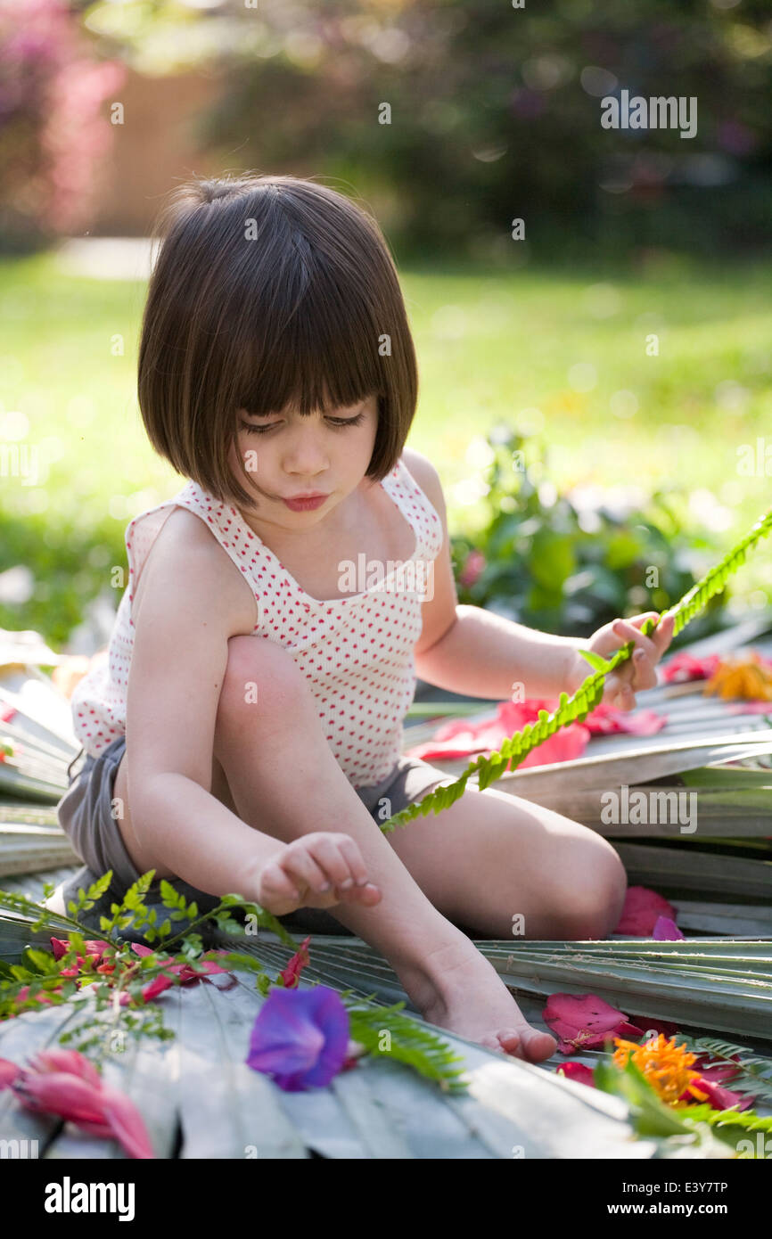 Girl with fern making flower and leaf display in garden Stock Photo