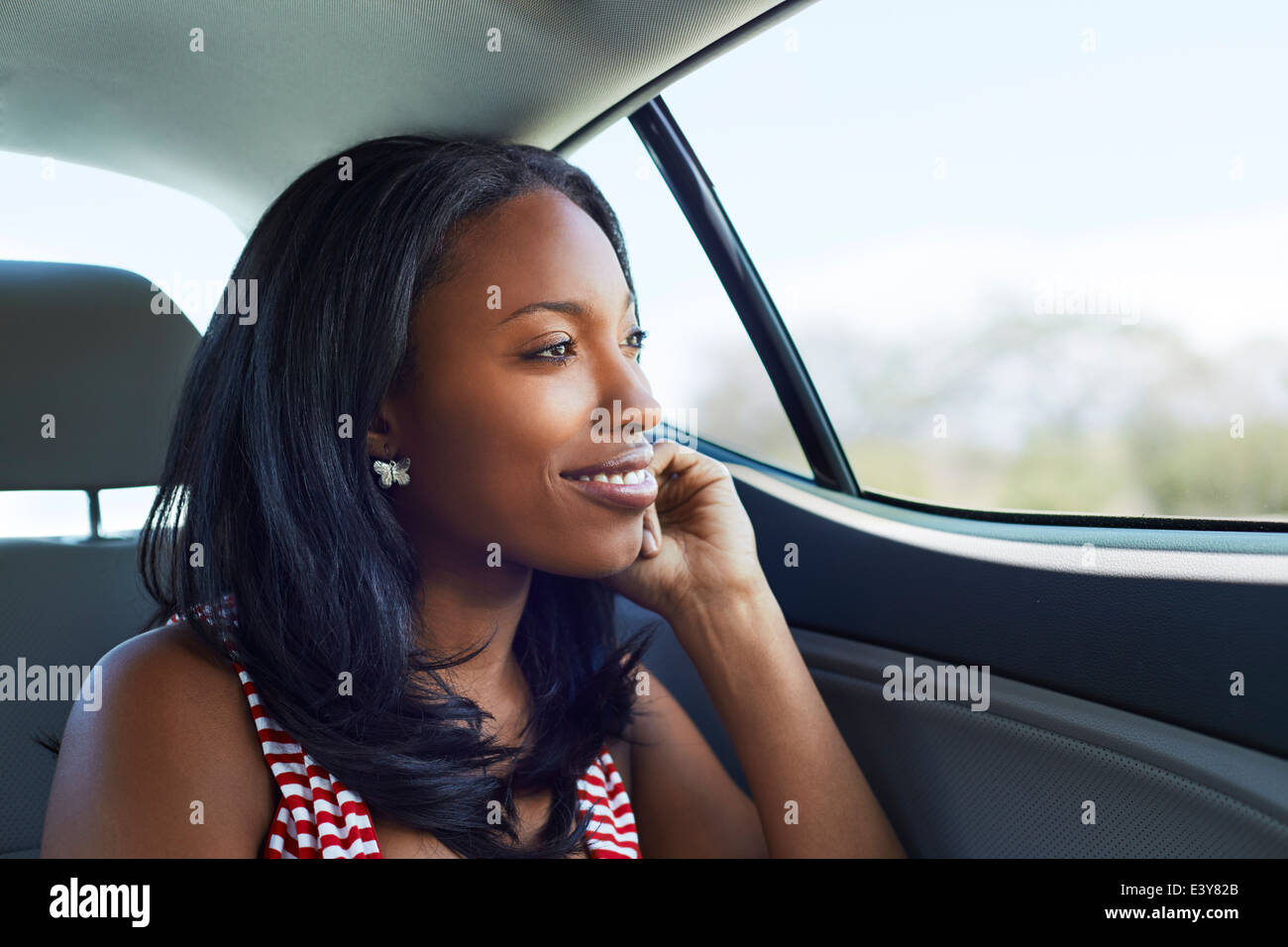 Portrait of young woman gazing through car backseat window Stock Photo