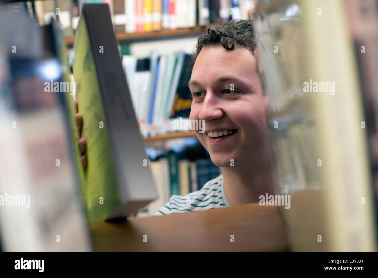 Young man choosing book in library Stock Photo