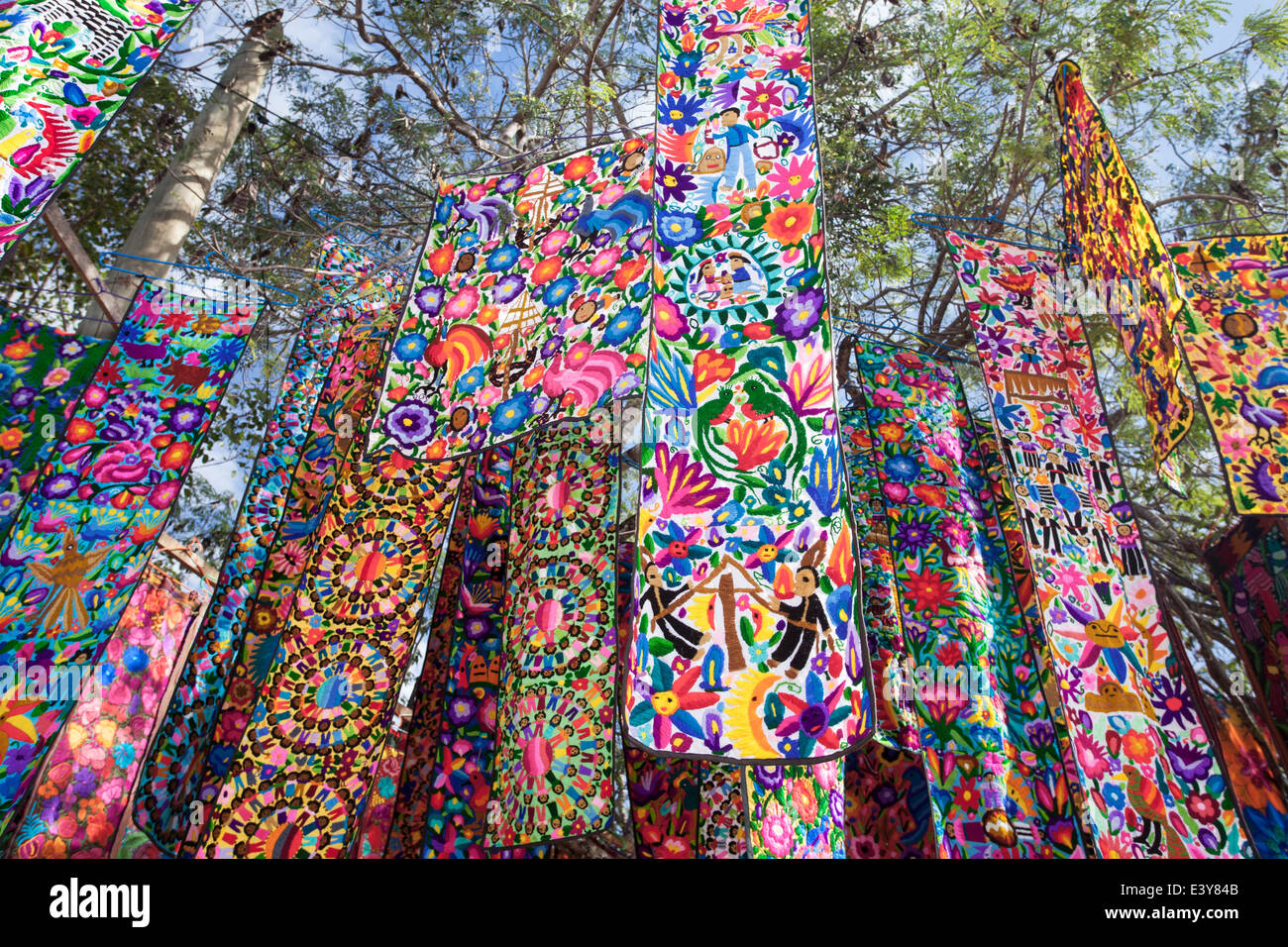 Hand stitched table runners hang from the trees in a Tulum, Mexico market. Stock Photo