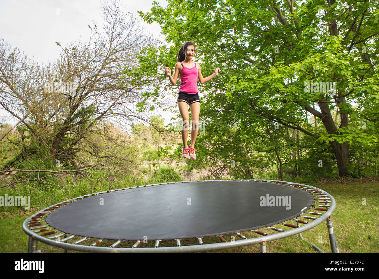 Teenage girl jumping on trampoline, outdoors Stock Photo