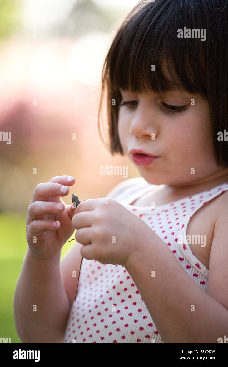 Close up portrait of girl holding lizard in garden Stock Photo
