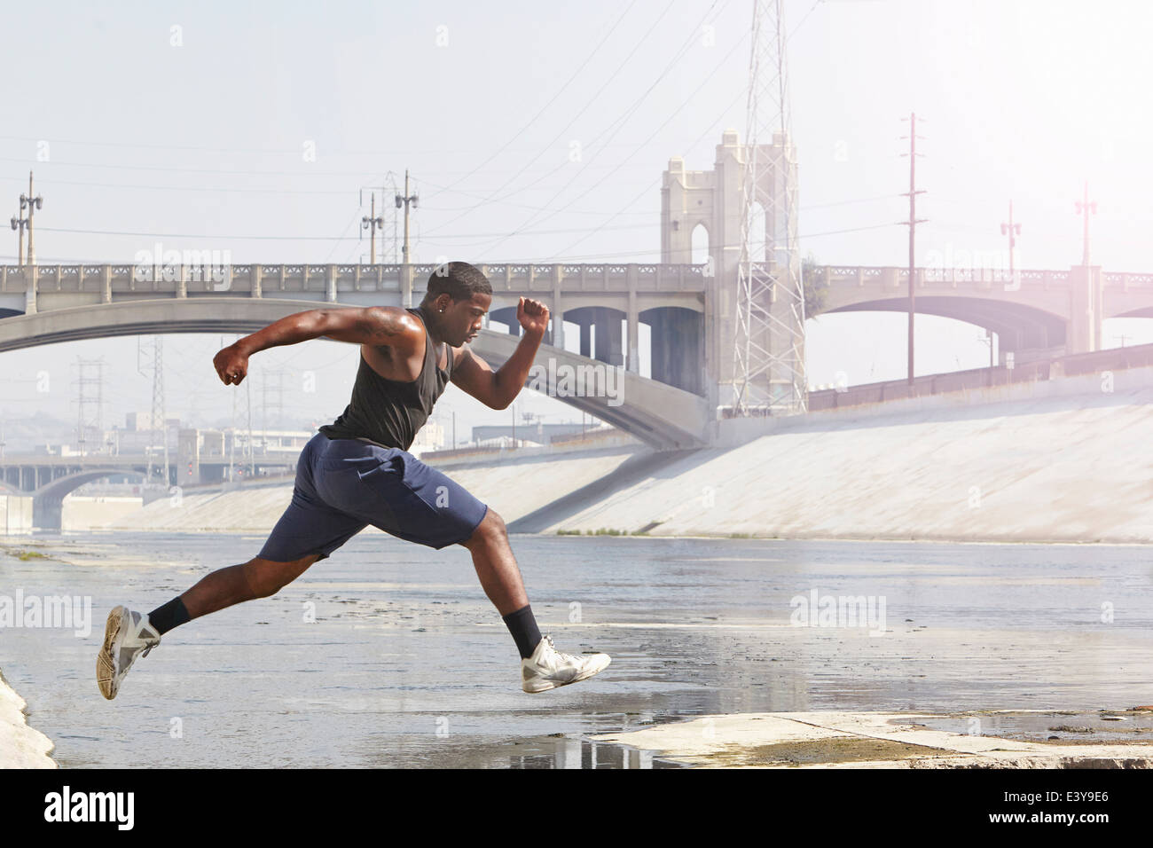 Young man speed running and jumping from riverbank Stock Photo