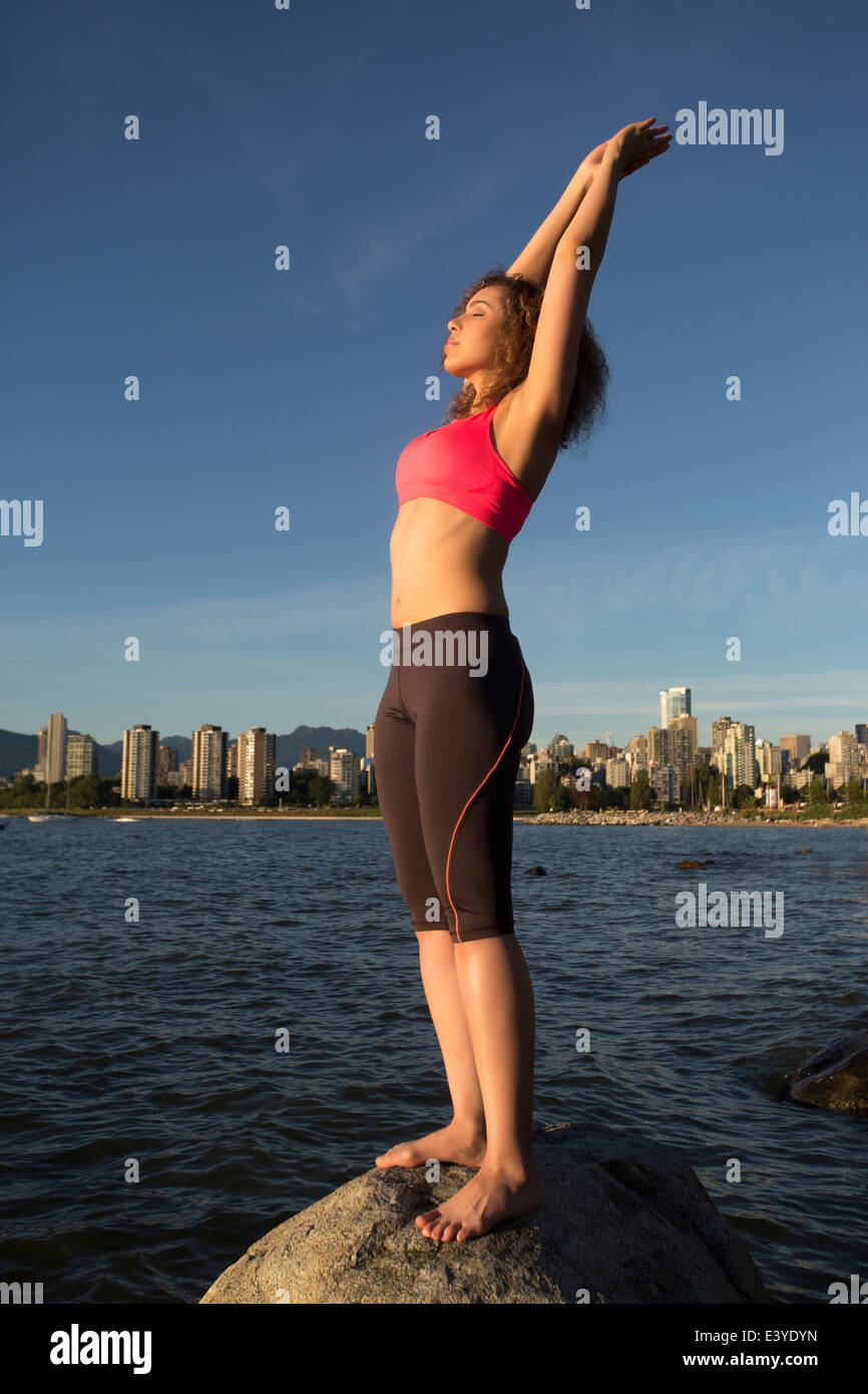 Woman doing yoga standing on a rock in the ocean in Vancouver, Canada. Stock Photo