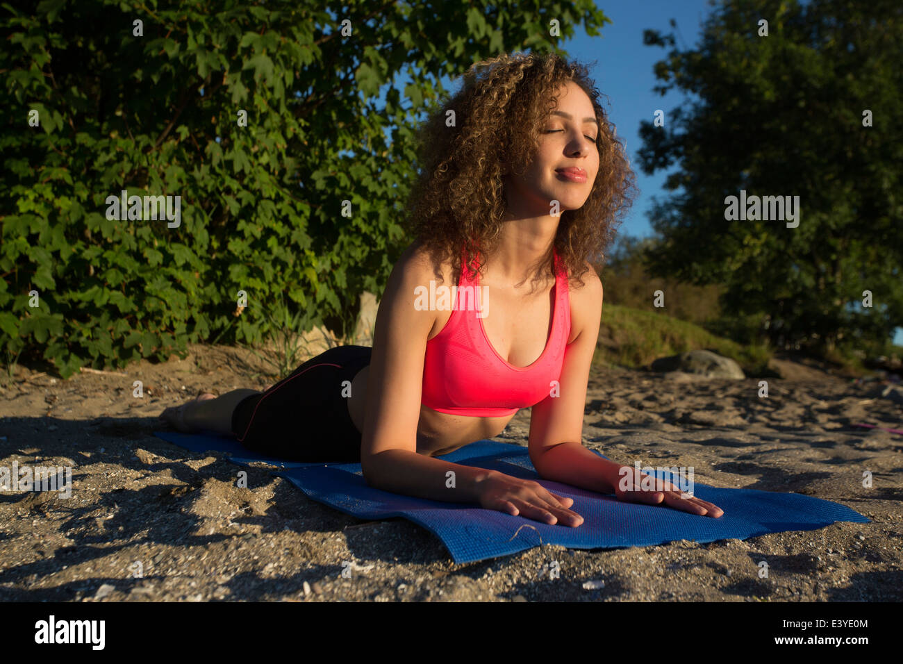 Girl doing yoga on the beach with eyes closed. Stock Photo