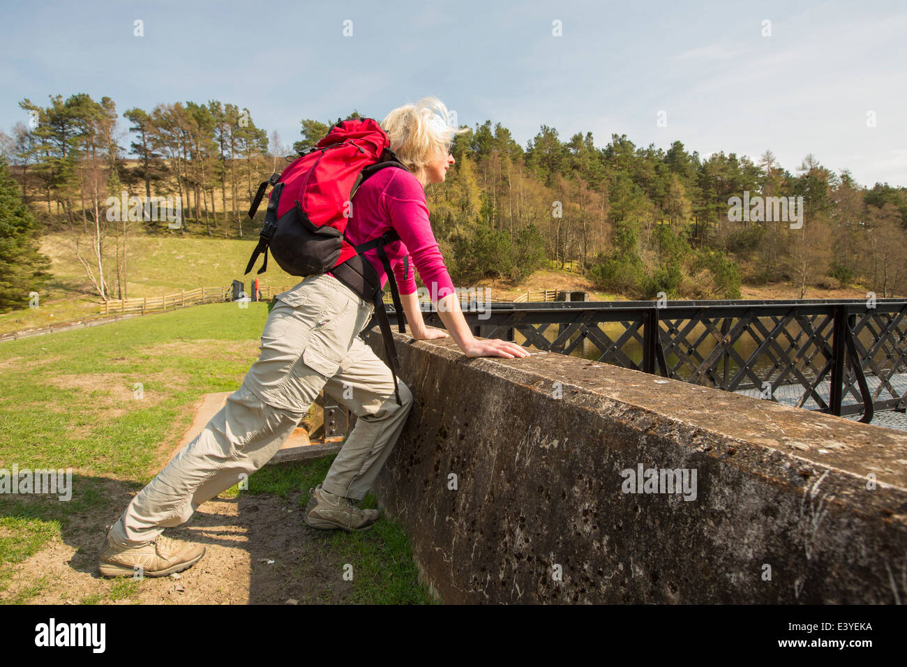 A woman stretching calf muscles on the dam of Cowgill lower Reservoir