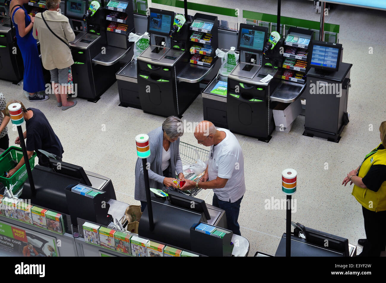 Elderly couple using self checkout till in supermarket Stock Photo