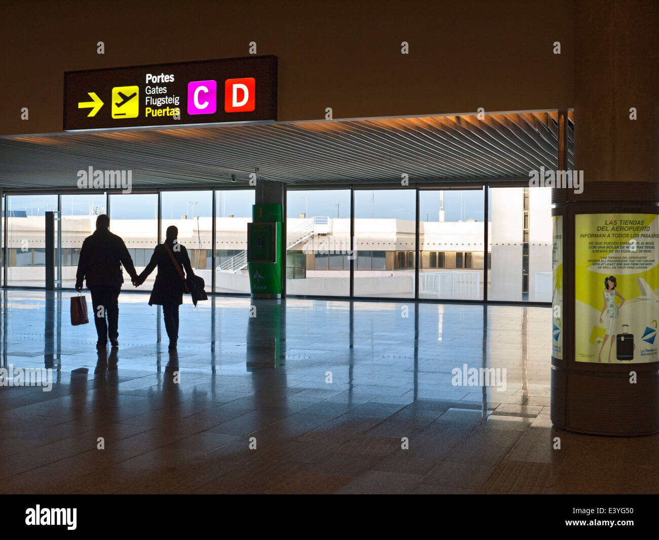 PALMA AIRPORT SPAIN Couple with duty free shopping bags walking hand in hand to airline departures gate in modern Spanish contemporary airport EU Stock Photo