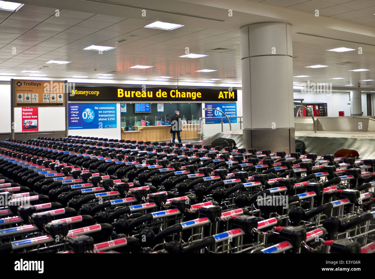 AIRPORT Quiet deserted arrivals terminal at Gatwick airport with lines of unused baggage trolleys and Bureau de Change London UK Stock Photo