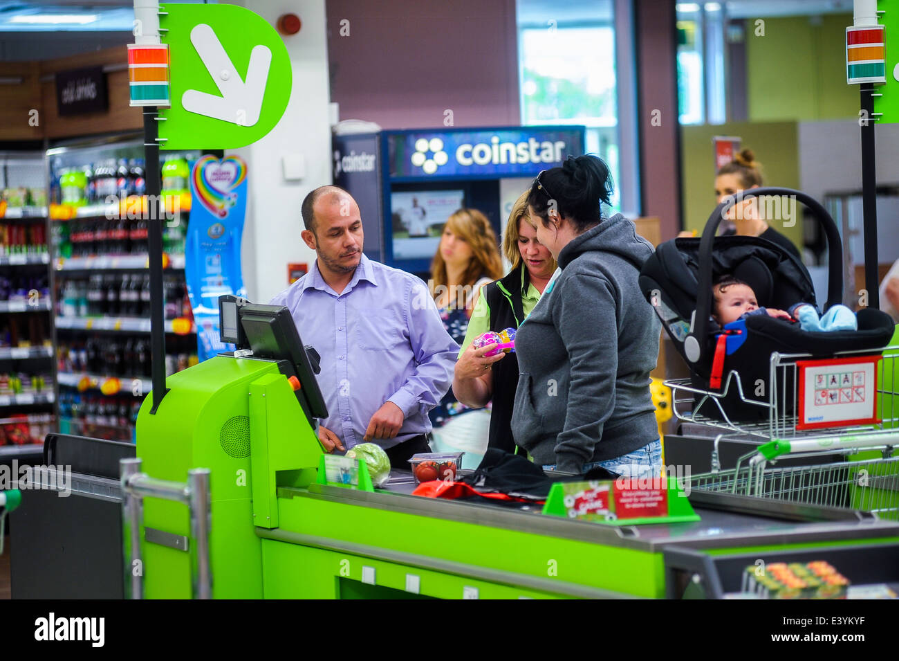 assistant helping couple use a self-service checkout in a supermarket Stock Photo