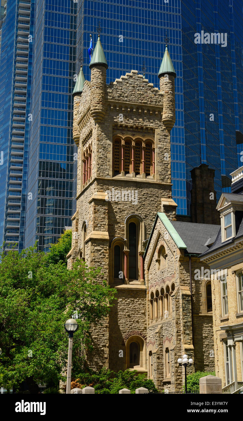 Golden stone of St Andrews presbyterian church tower against modern blue glass highrise office tower Toronto Canada Stock Photo
