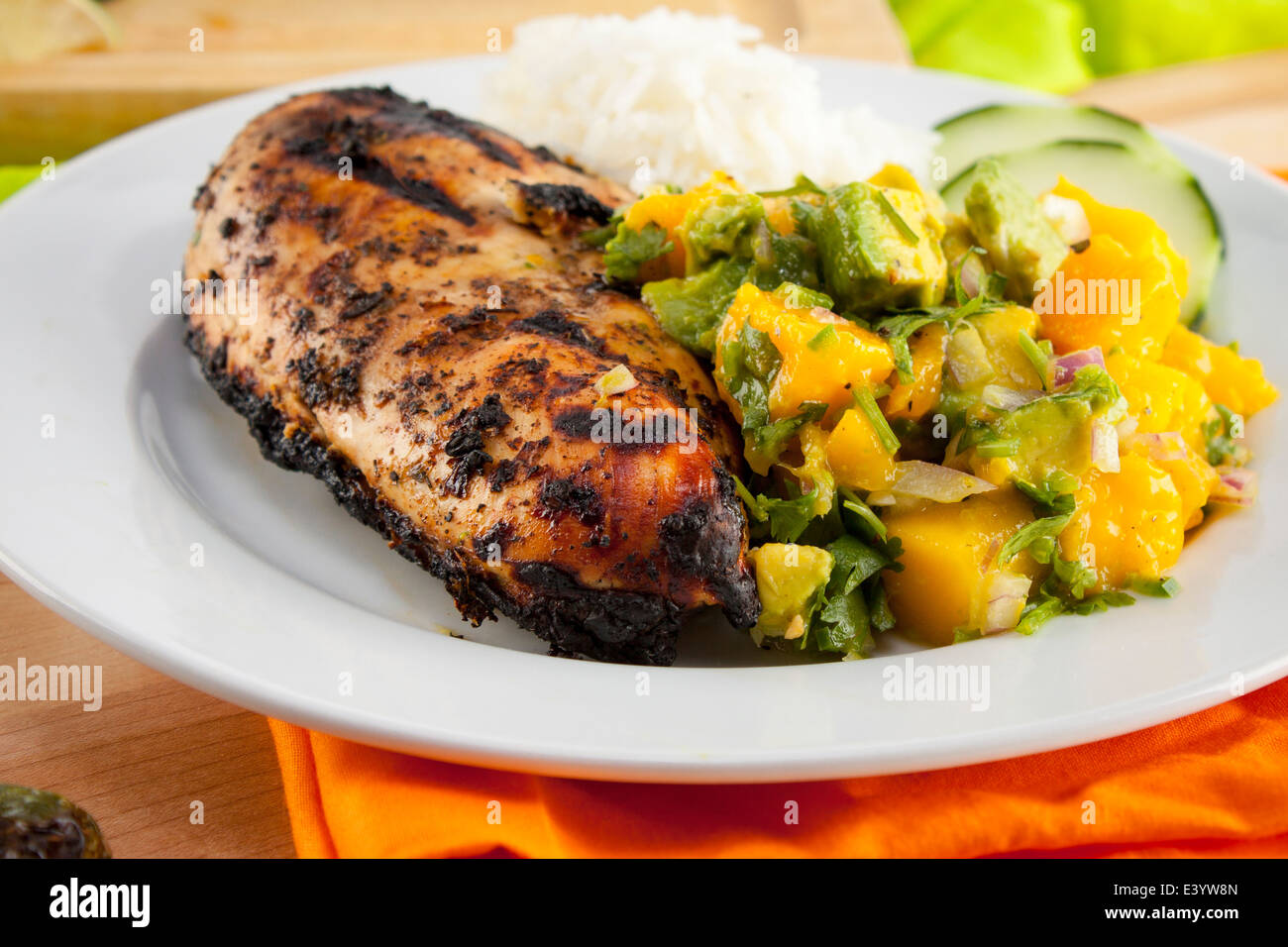 Grilled jJerk chicken meal. Sliced cucumber, mango salad Stock Photo Alamy