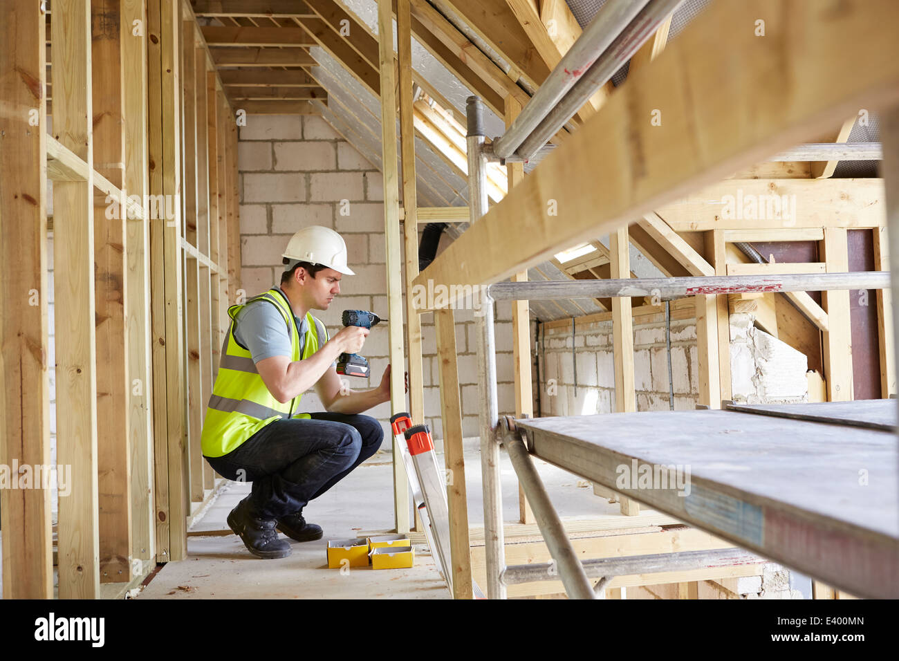 Construction Worker Using Drill On House Build Stock Photo