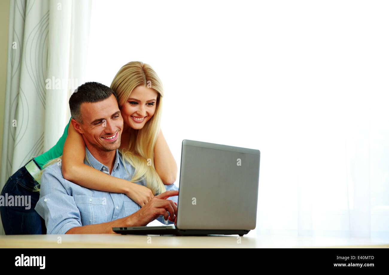 Happy couple using laptop together at home Stock Photo - Alamy